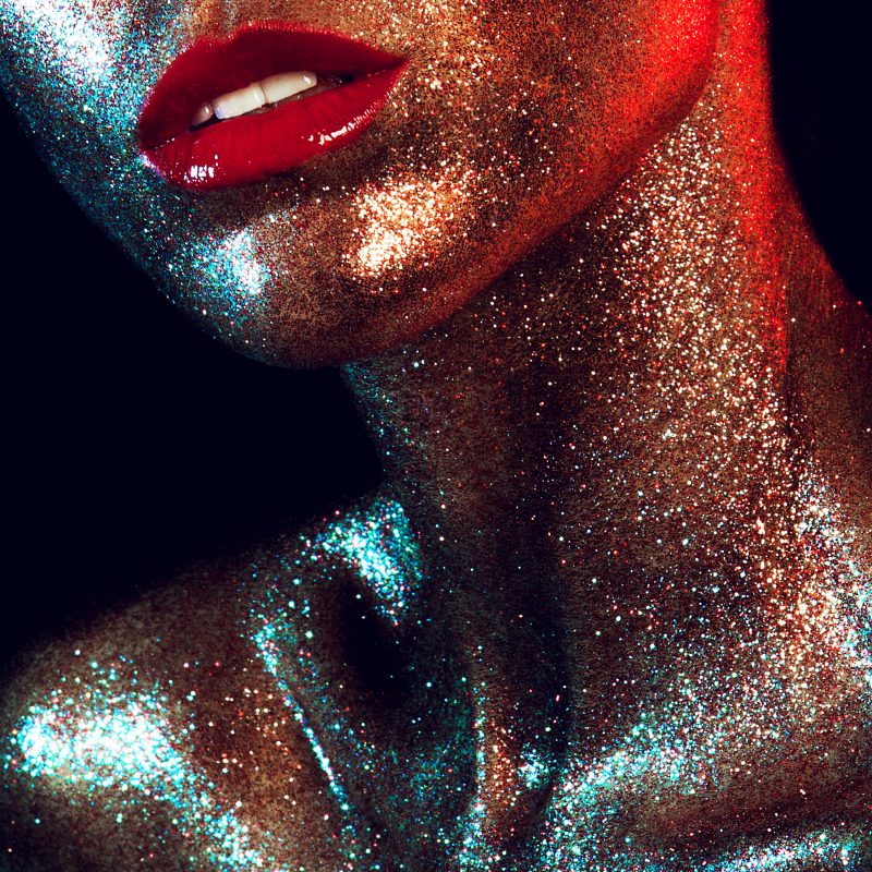 Beautyful girl with gold glitter on her face and red lips